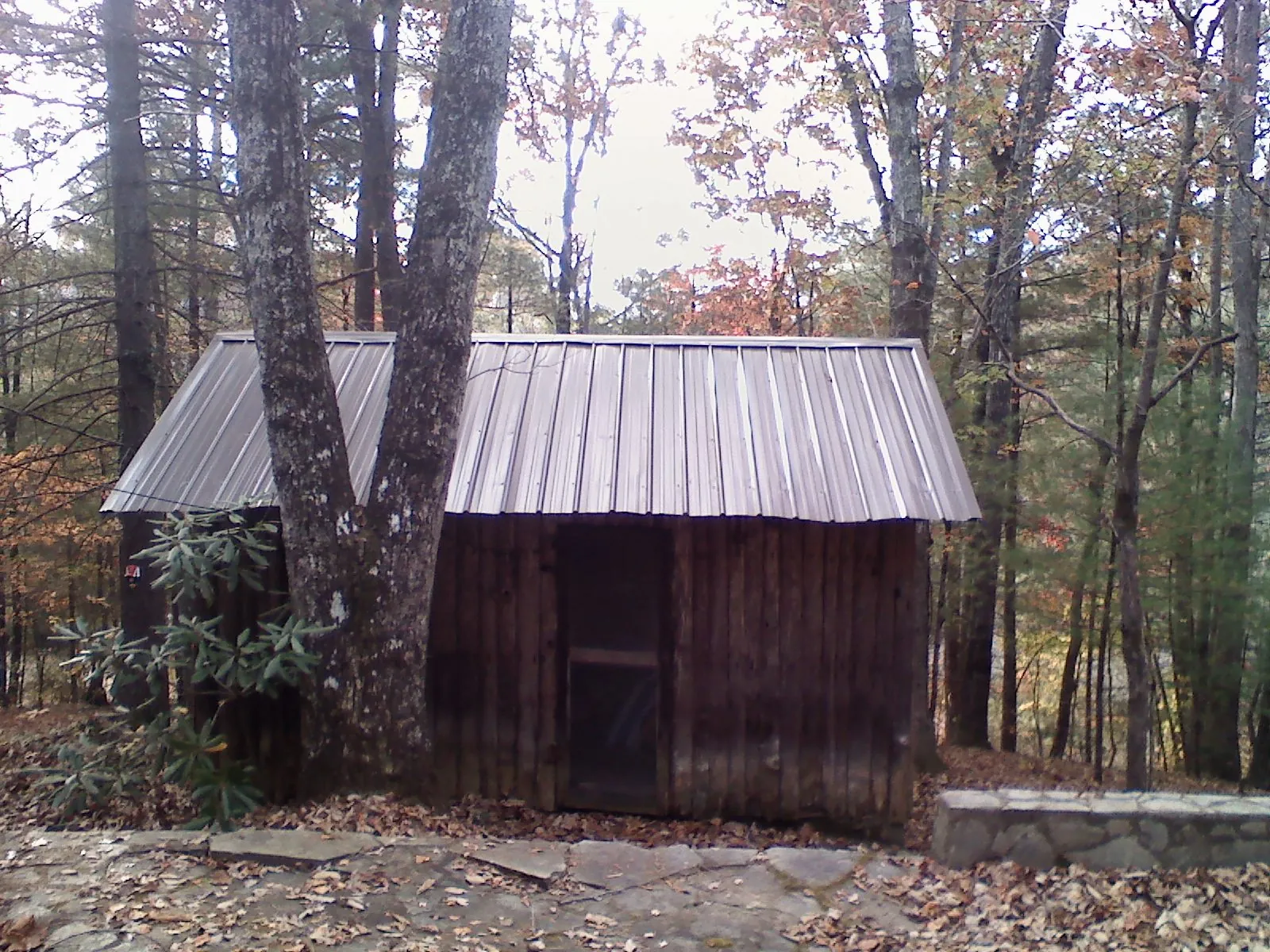 New metal gable roof on a small log shed among the trees in Fort Atkinson