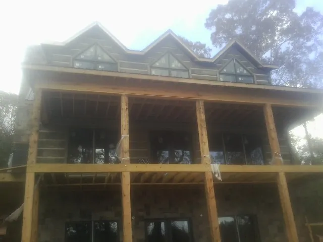 Dormers and porch framing on a large log home under construction — Roof Coating work by our crew in Fort Atkinson