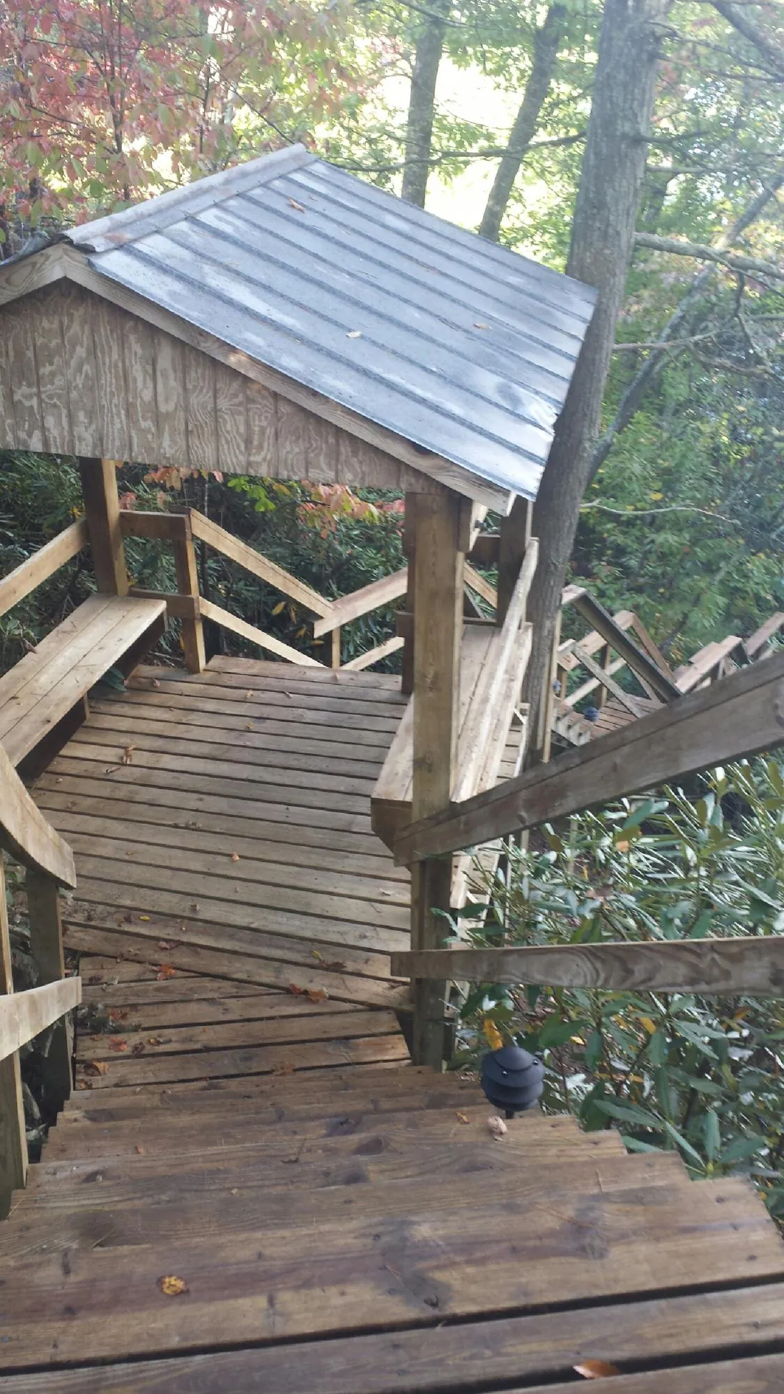 Metal roofed shelter over wooden steps on a wooded walkway — Skylight Repair & Installation work by our crew in Fort Atkinson