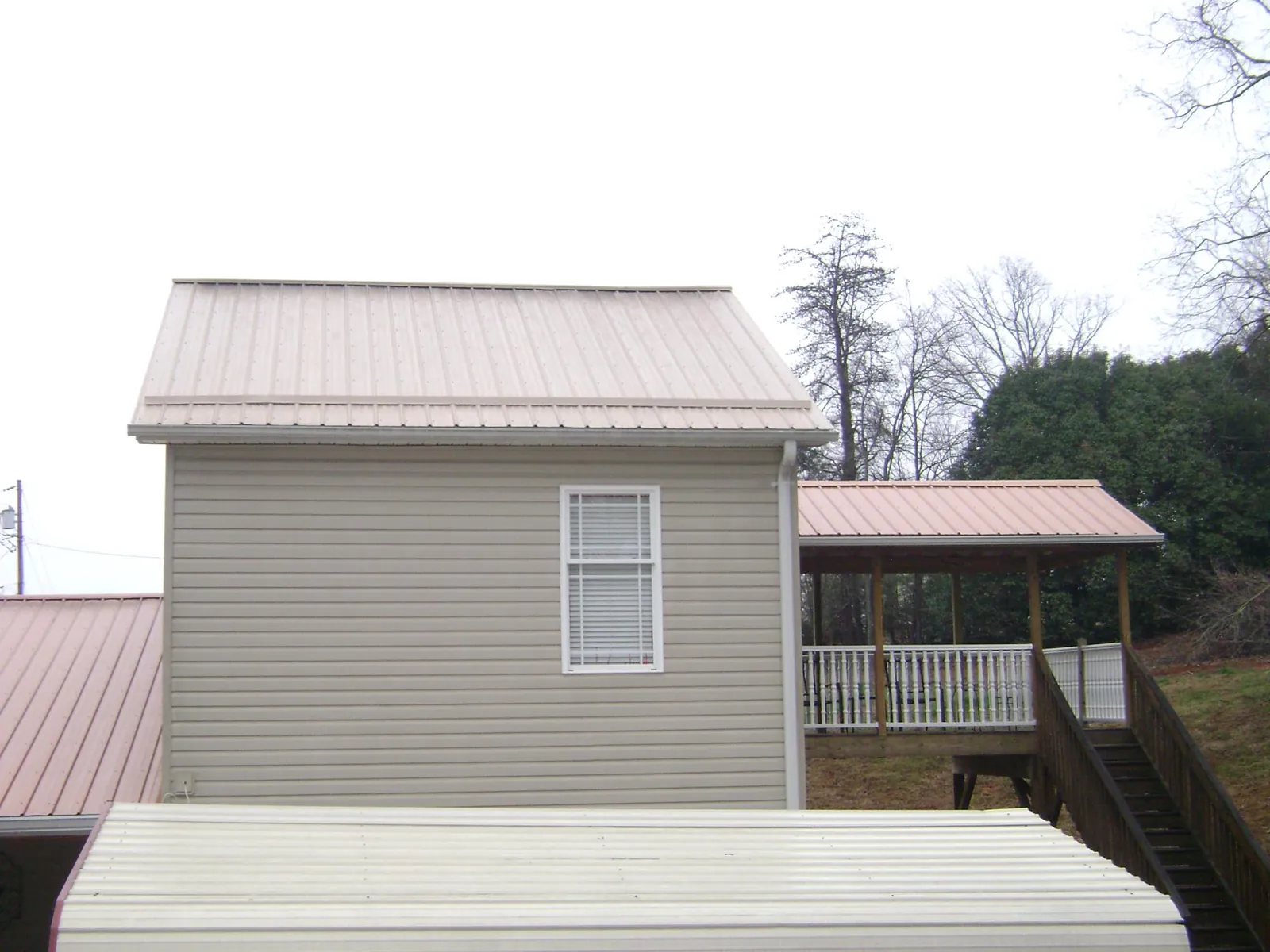 Tan metal roofs on a two story addition and attached porch, from a Roof Replacement job in Fort Atkinson